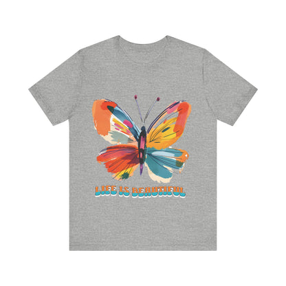 Colorful cartoon-style butterfly with vibrant wings and the text 'Life is Beautiful' designed for t-shirts in colors including Aqua, Athletic Heather, Berry, Black, Dark Grey Heather, Heather Red, Heather Team Purple, Heather True Royal, White, and Charity Pink.