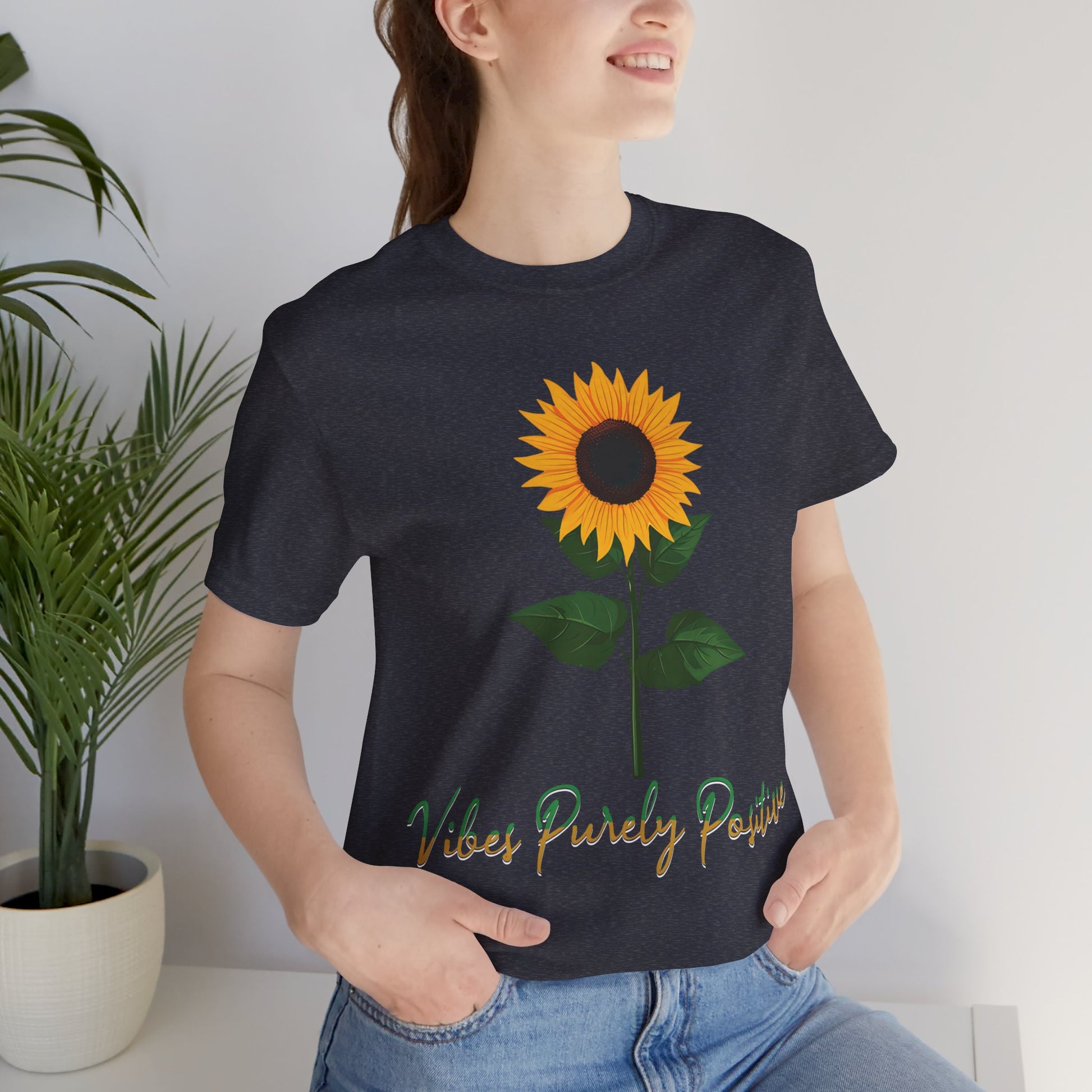 Sunflower illustration with 'Vibes Purely Positive' phrase - a vibrant sunflower with yellow petals and dark brown center, green leaves on a stem, conveying a positive message printed in t-shirts of different colors like "Army Athletic Heather Berry Black Heather Navy Heather Team Purple Navy White Ash Heather Aqua"