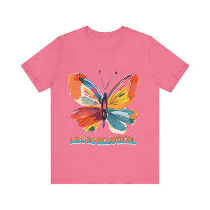 Colorful cartoon-style butterfly with vibrant wings and the text 'Life is Beautiful' designed for t-shirts in colors including Aqua, Athletic Heather, Berry, Black, Dark Grey Heather, Heather Red, Heather Team Purple, Heather True Royal, White, and Charity Pink