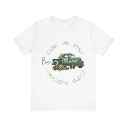 Vintage boho-style illustration of an old green truck surrounded by colorful flowers, with the text 'Be Genuine - Bold - Optimistic - Compassionate - Kind - Yourself.' This design is intended for t-shirts in various colors, including Aqua, Athletic Heather, Black, Dark Grey Heather, Heather Kelly, Heather Navy, Heather Red, Heather True Royal, Kelly, Pink, White, Yellow, Heather Aqua, Heather Ice Blue, Heather Mauve, and Charity Pink.