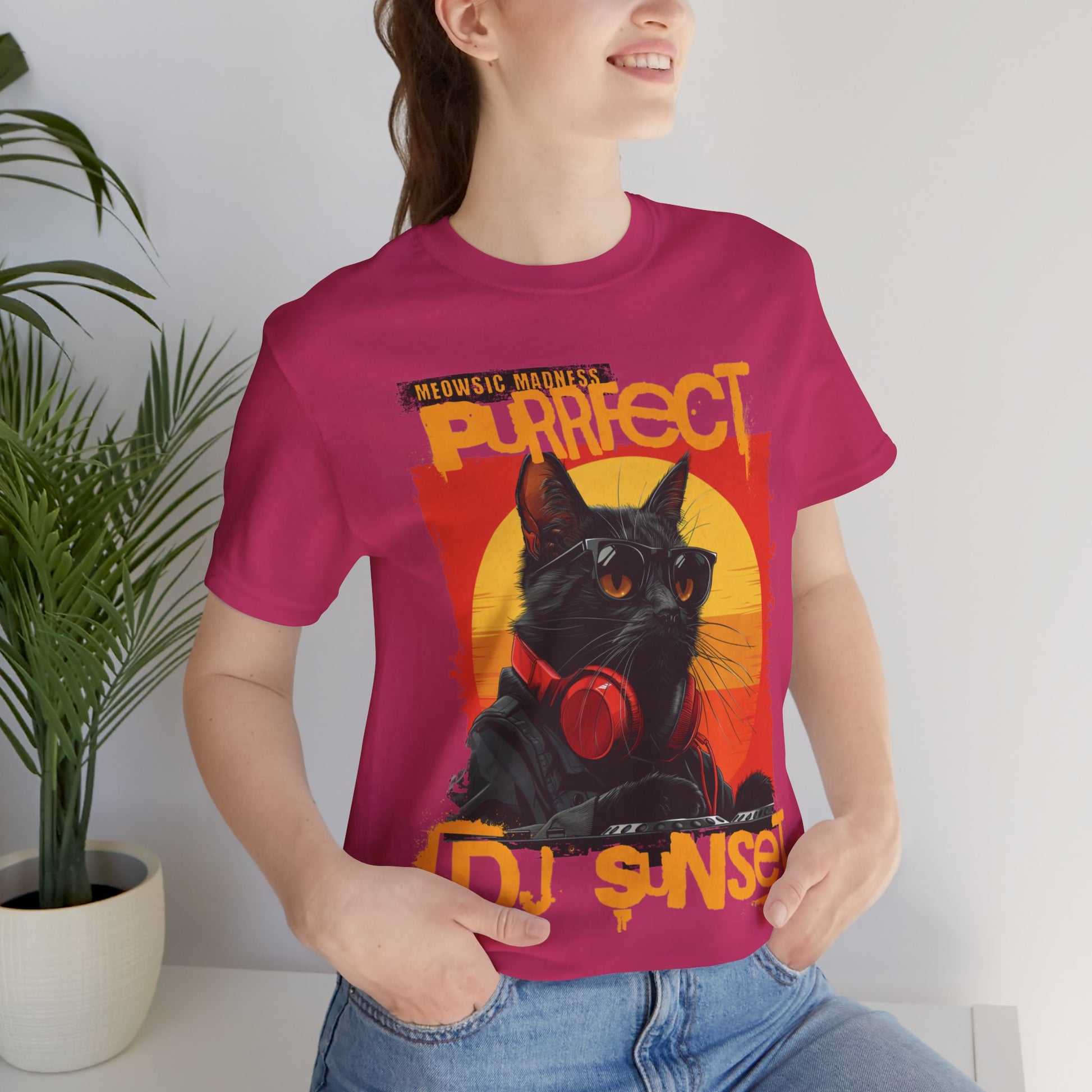 “Turntable Feline: The Sunset DJ Cat – A charismatic black cat dons DJ gear, complete with sunglasses and headphones, set against a vibrant sunset-inspired backdrop, with ‘Meowsic Madness’ and ‘Purrfect’ emblazoned above, capturing the essence of a purrfectly orchestrated music event printed in different t-shirts colors like Athletic Heather Berry Black Dark Grey Heather Heather Navy Navy Ash.” 