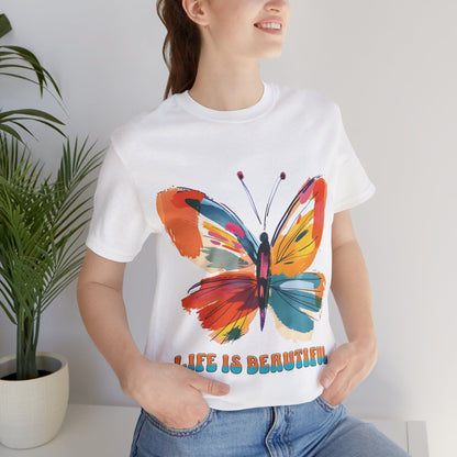 Colorful cartoon-style butterfly with vibrant wings and the text 'Life is Beautiful' designed for t-shirts in colors including Aqua, Athletic Heather, Berry, Black, Dark Grey Heather, Heather Red, Heather Team Purple, Heather True Royal, White, and Charity Pink