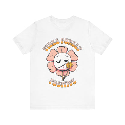 Cute pink flower with a smiling face and a yellow flower in its mouth, accompanied by the text "Vibes Purely Positive." This cheerful design is perfect for t-shirts available in colors Aqua, Berry, Black, Dark Gray, Heather Kelly, Heather Team Purple, Heather True Royal, Navy, White, and Charity Pink.