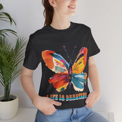 Colorful cartoon-style butterfly with vibrant wings and the text 'Life is Beautiful' designed for t-shirts in colors including Aqua, Athletic Heather, Berry, Black, Dark Grey Heather, Heather Red, Heather Team Purple, Heather True Royal, White, and Charity Pink