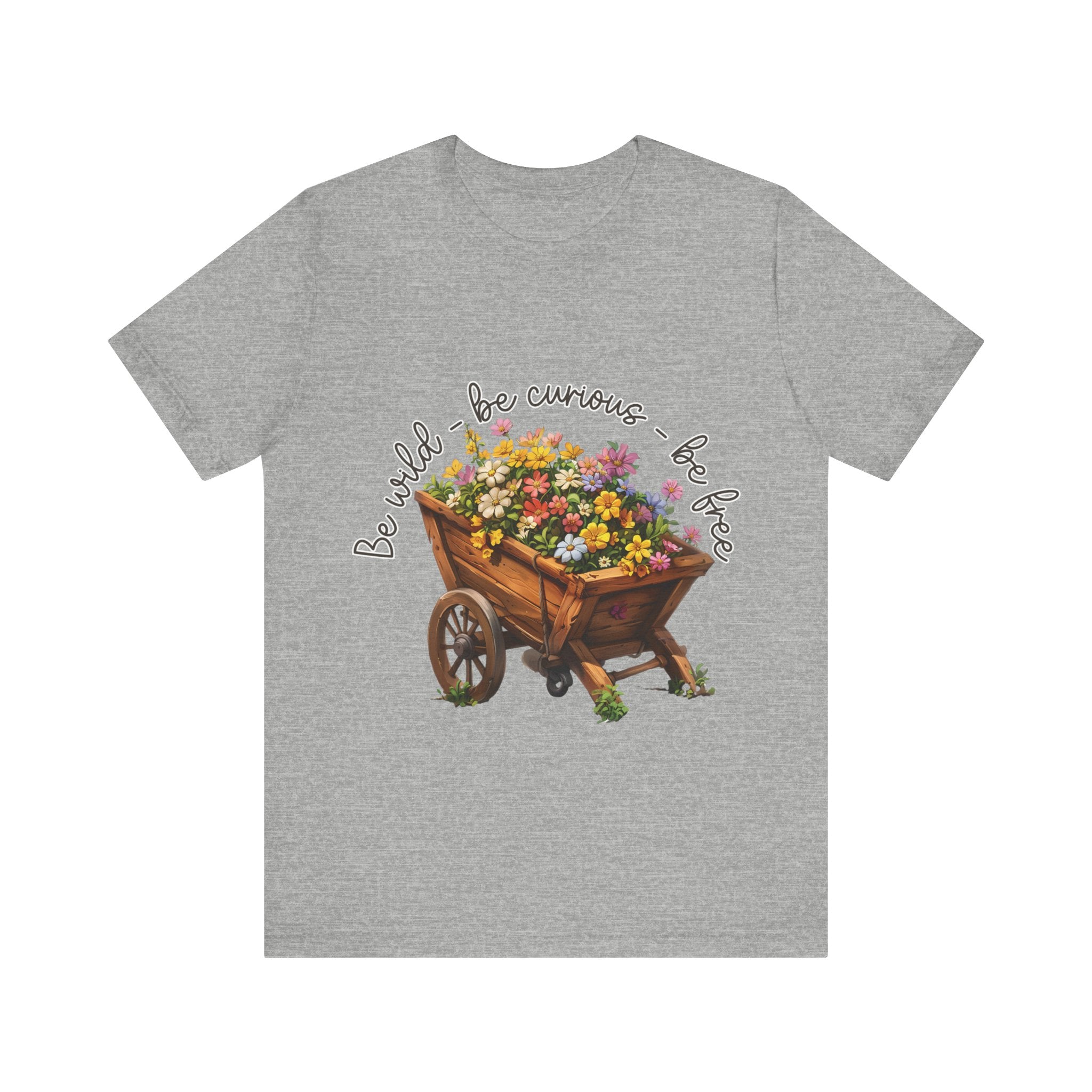 Colorful illustration of a wooden wheelbarrow filled with vibrant flowers, surrounded by the handwritten text 'Be wild - be curious - be free.' This design is intended for t-shirts in various colors, including Aqua, Athletic Heather, Black, Dark Grey Heather, Heather Kelly, Heather Red, Heather True Royal, Natural, Navy, Pink, White, Heather Aqua, Heather Ice Blue, Heather Mauve, and Charity Pink.