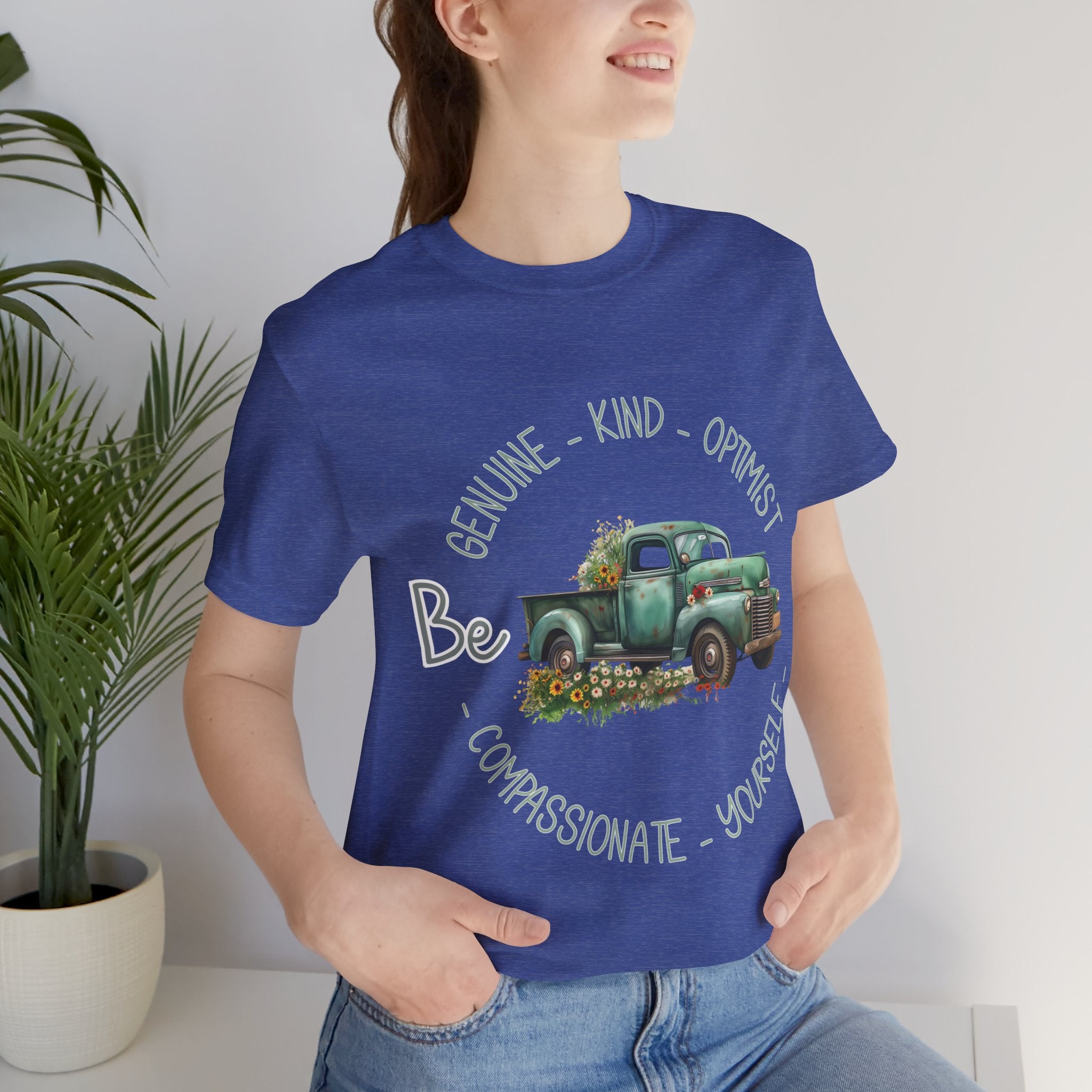 Vintage boho-style illustration of an old green truck surrounded by colorful flowers, with the text 'Be Genuine - Bold - Optimistic - Compassionate - Kind - Yourself.' This design is intended for t-shirts in various colors, including Aqua, Athletic Heather, Black, Dark Grey Heather, Heather Kelly, Heather Navy, Heather Red, Heather True Royal, Kelly, Pink, White, Yellow, Heather Aqua, Heather Ice Blue, Heather Mauve, and Charity Pink.