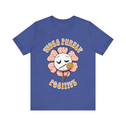 Cute pink flower with a smiling face and a yellow flower in its mouth, accompanied by the text "Vibes Purely Positive." This cheerful design is perfect for t-shirts available in colors Aqua, Berry, Black, Dark Gray, Heather Kelly, Heather Team Purple, Heather True Royal, Navy, White, and Charity Pink.