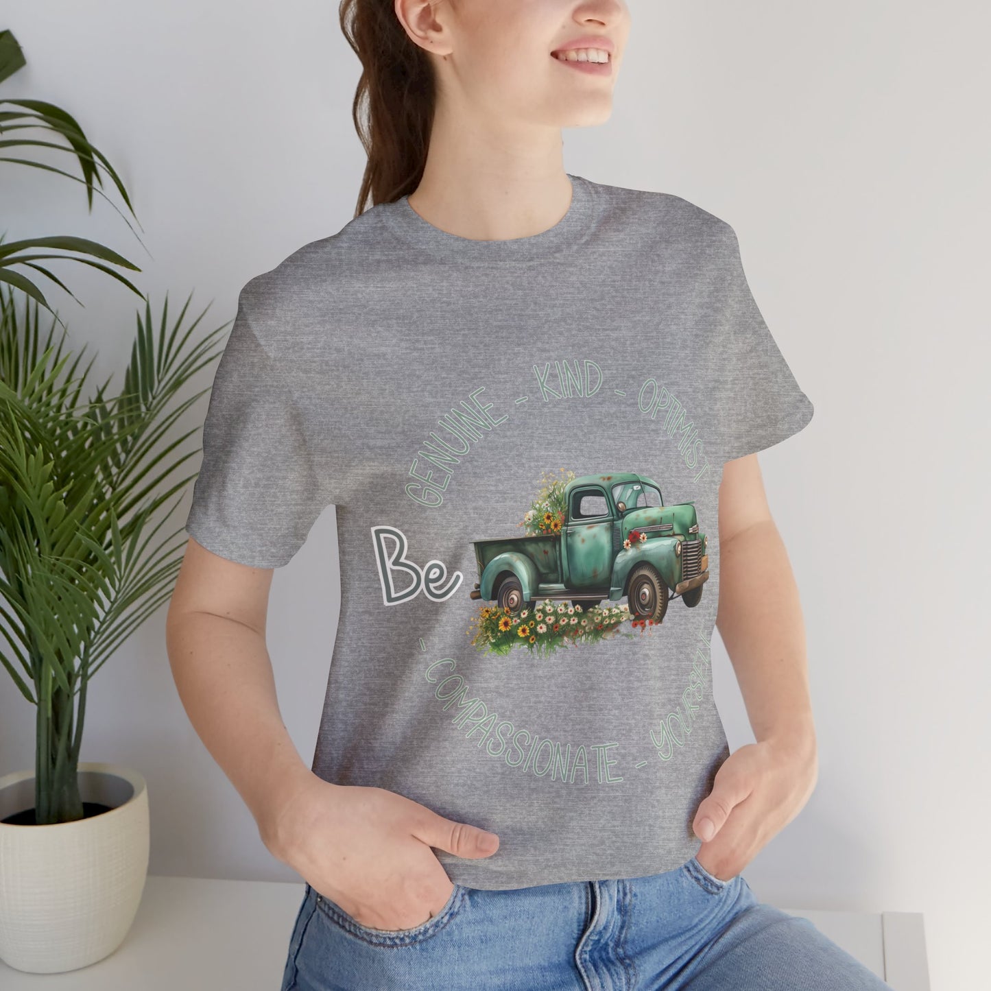 Vintage boho-style illustration of an old green truck surrounded by colorful flowers, with the text 'Be Genuine - Bold - Optimistic - Compassionate - Kind - Yourself.' This design is intended for t-shirts in various colors, including Aqua, Athletic Heather, Black, Dark Grey Heather, Heather Kelly, Heather Navy, Heather Red, Heather True Royal, Kelly, Pink, White, Yellow, Heather Aqua, Heather Ice Blue, Heather Mauve, and Charity Pink.